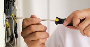Hands using a screwdriver during electrical repair work